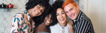 Four friends smiling, hanging out in a kitchen